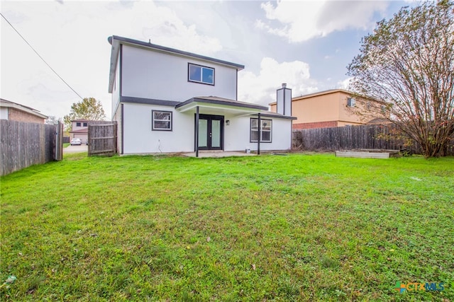 rear view of property with a lawn, a patio area, and french doors