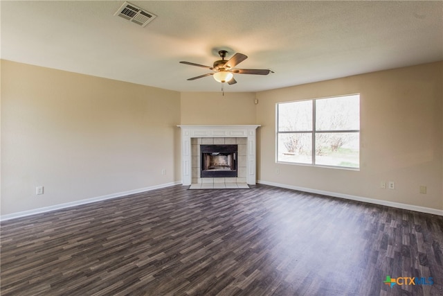 unfurnished living room with ceiling fan, dark hardwood / wood-style flooring, a textured ceiling, and a tile fireplace