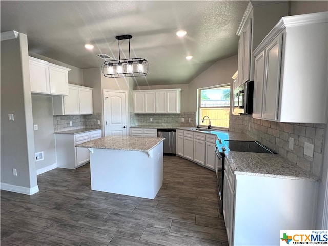 kitchen featuring a center island, vaulted ceiling, white cabinetry, appliances with stainless steel finishes, and decorative light fixtures