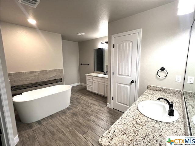 bathroom with hardwood / wood-style floors, vanity, and a tub