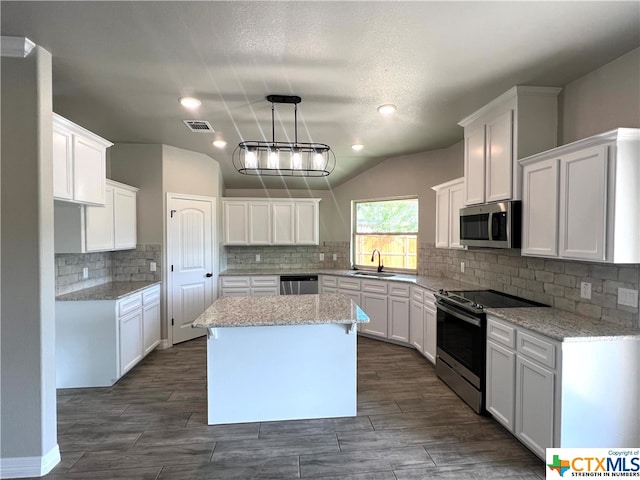 kitchen with a center island, white cabinets, decorative light fixtures, and stainless steel appliances