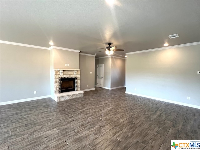 unfurnished living room with crown molding, a stone fireplace, a textured ceiling, dark hardwood / wood-style floors, and ceiling fan