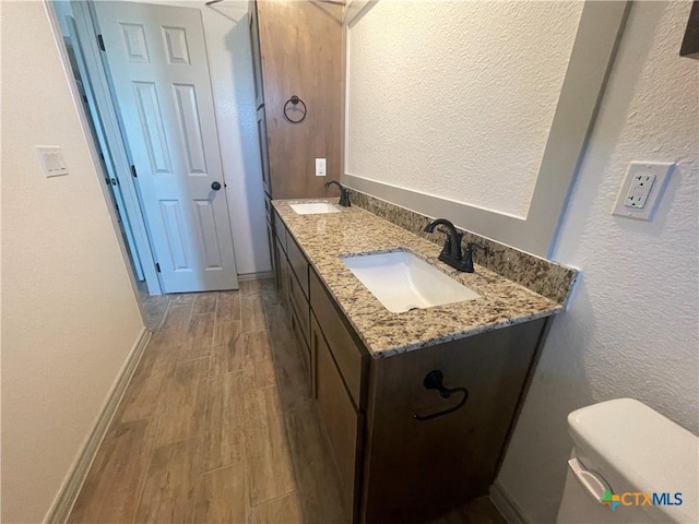 2408 Duntov Dr, Temple, TX 76504 - bathroom with double vanity, wood finished floors, a textured wall, toilet, and baseboards