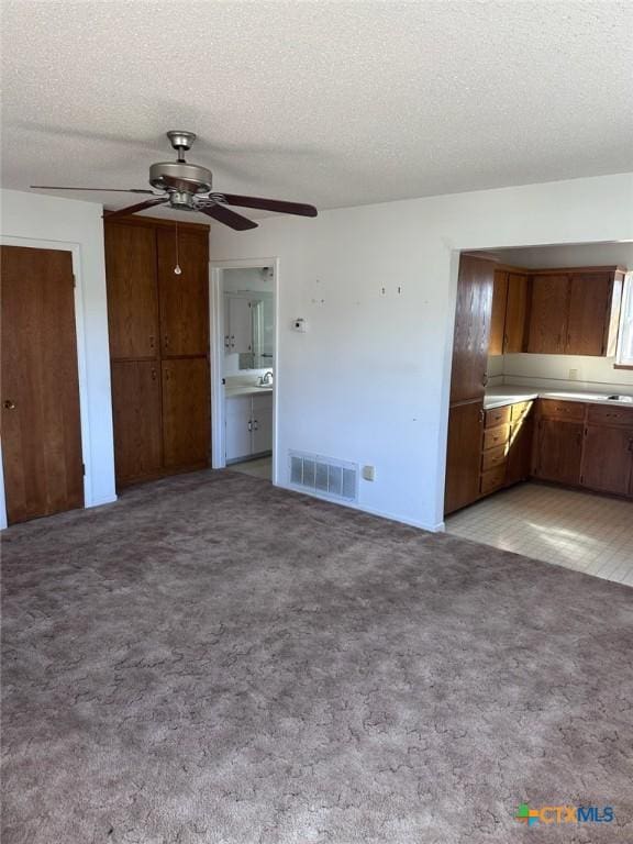 unfurnished bedroom featuring visible vents, light colored carpet, ensuite bath, and a textured ceiling