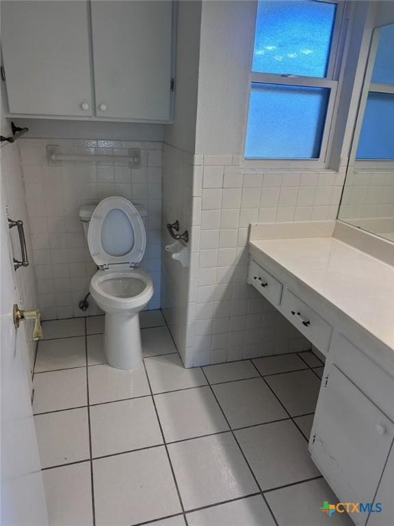 half bath featuring tile patterned flooring, tile walls, toilet, and vanity