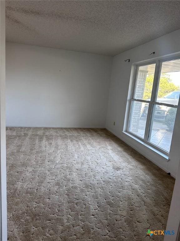 carpeted empty room featuring a textured ceiling