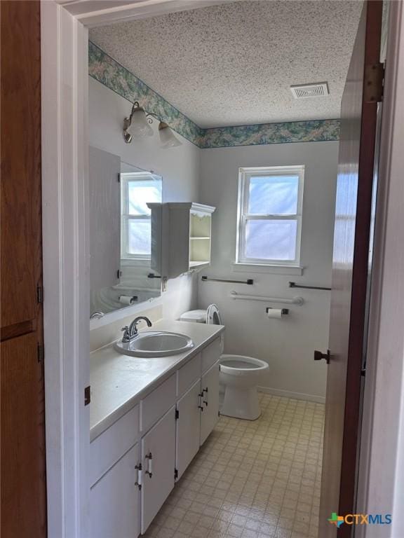 bathroom with visible vents, a textured ceiling, toilet, and vanity