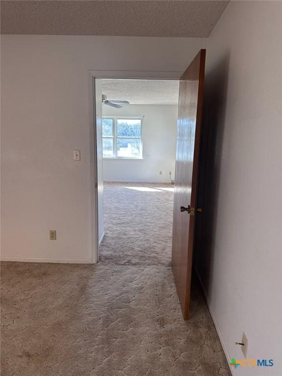 hall with carpet, baseboards, and a textured ceiling