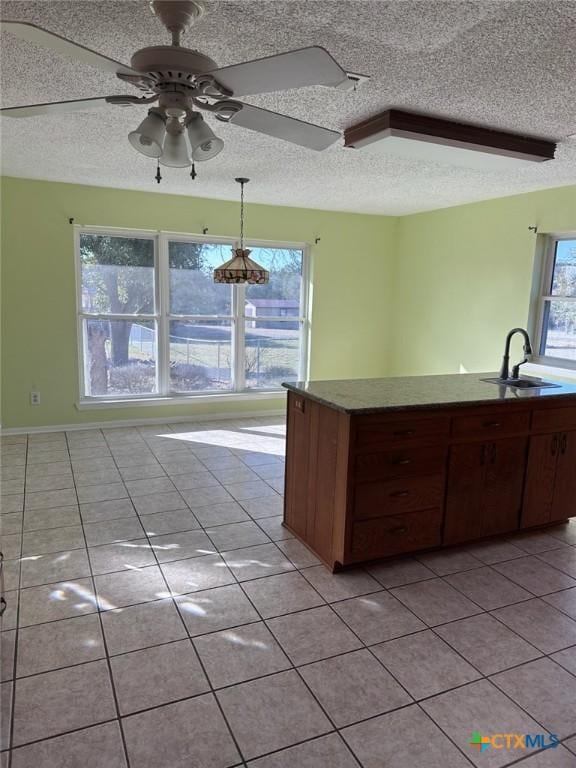 kitchen with a textured ceiling, light tile patterned flooring, a ceiling fan, and a sink