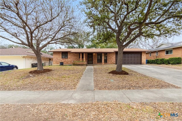 ranch-style home with driveway, brick siding, and an attached garage