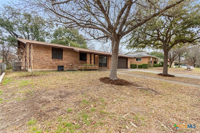 ranch-style home with an attached garage, fence, concrete driveway, and brick siding