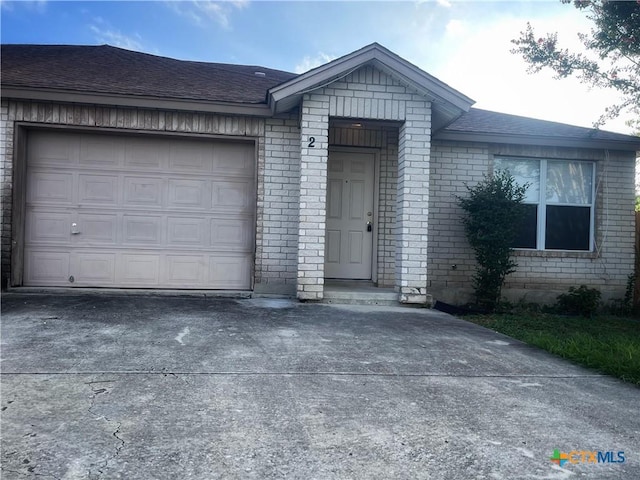 ranch-style house with an attached garage, brick siding, driveway, and a shingled roof