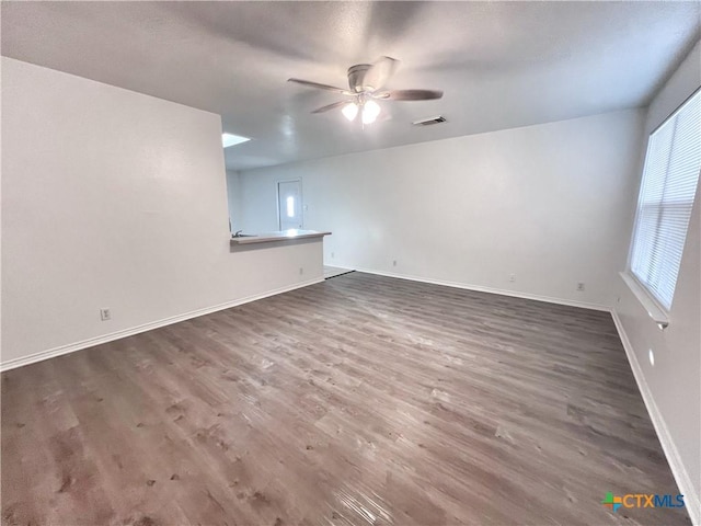 spare room with ceiling fan, visible vents, baseboards, and wood finished floors