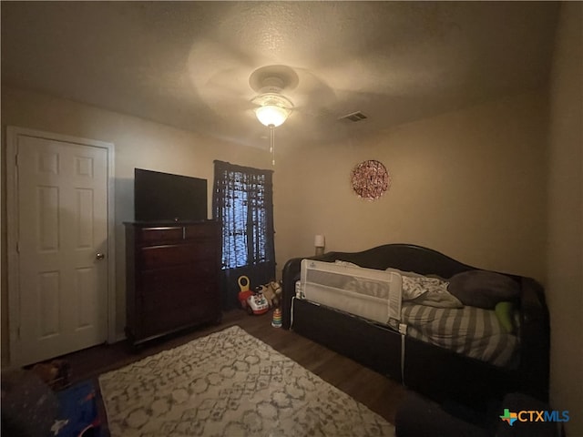 bedroom with ceiling fan, visible vents, and wood finished floors