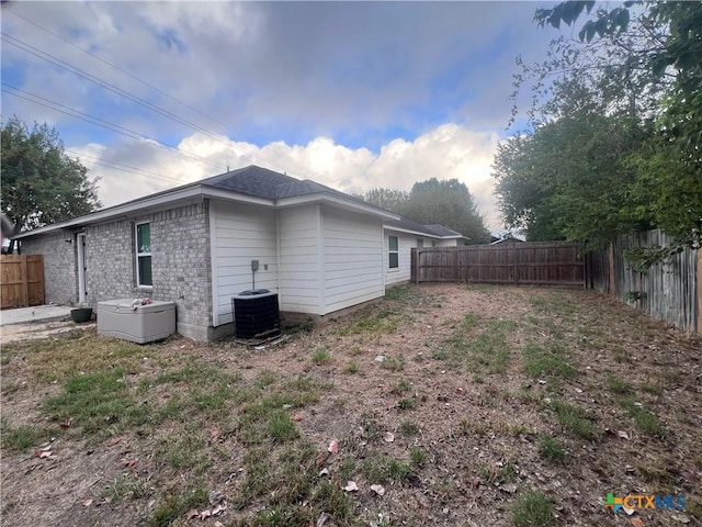 view of side of home featuring a fenced backyard, brick siding, and central AC