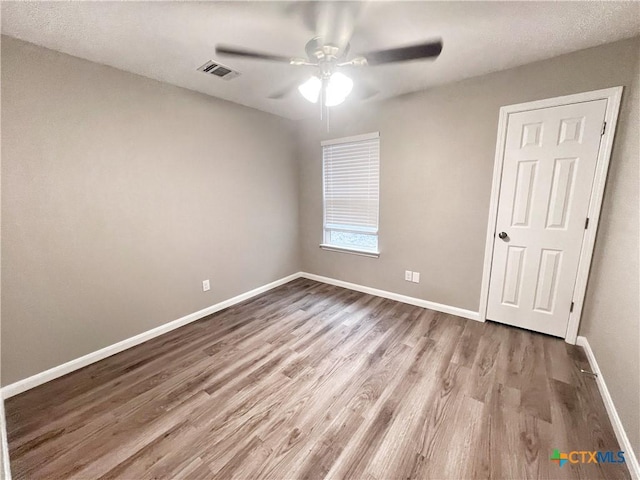 spare room featuring visible vents, baseboards, wood finished floors, and a ceiling fan