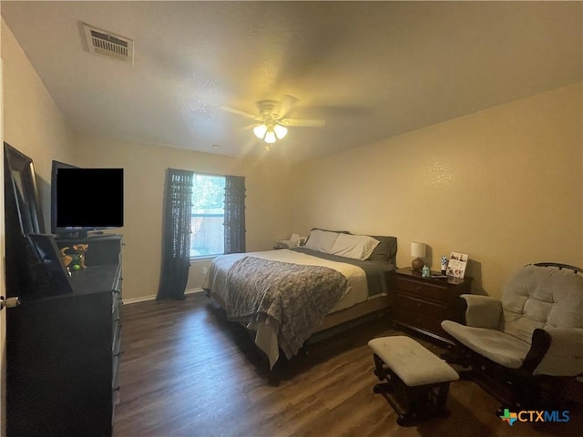 bedroom with baseboards, dark wood-style floors, visible vents, and ceiling fan