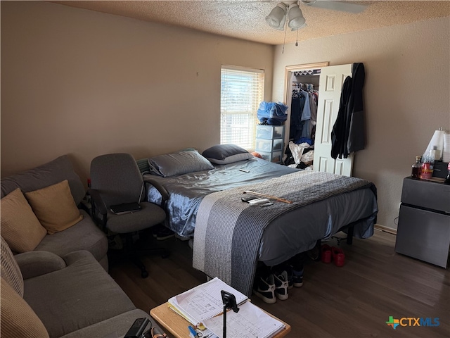 bedroom with ceiling fan, a spacious closet, dark wood-type flooring, a textured ceiling, and a closet