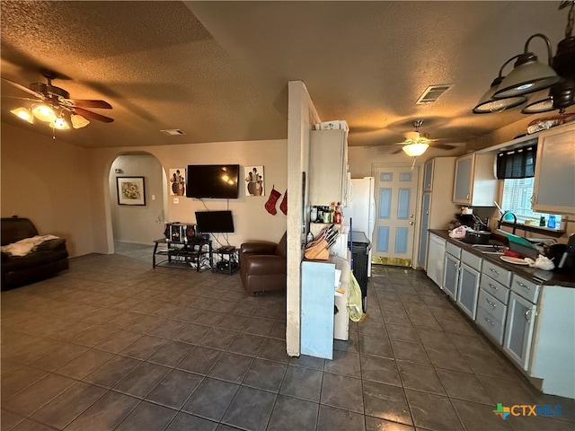 kitchen with a textured ceiling, white cabinetry, ceiling fan, and sink