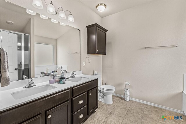 853 Hobby Rd, Copperas Cove, TX 76522 - full bathroom with baseboards, double vanity, toilet, tile patterned flooring, and a shower with door