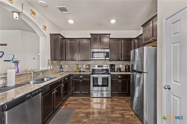 853 Hobby Rd, Copperas Cove, TX 76522 - kitchen featuring appliances with stainless steel finishes, dark brown cabinetry, dark wood-type flooring, and arched walkways