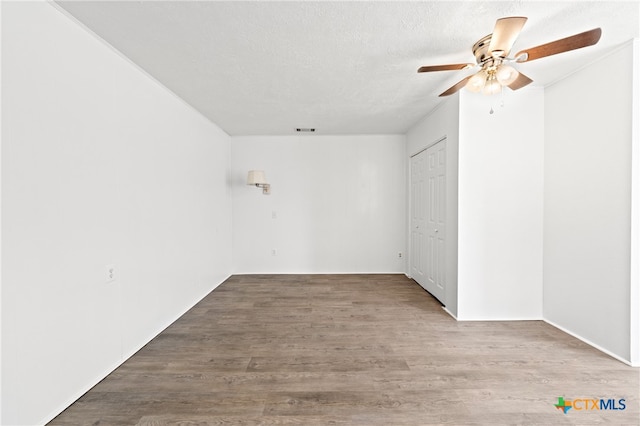 empty room featuring hardwood / wood-style floors, ceiling fan, and a textured ceiling