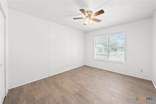 empty room with hardwood / wood-style flooring, ceiling fan, and a textured ceiling