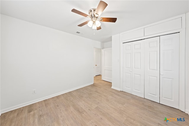 unfurnished bedroom featuring ceiling fan, a closet, and light wood-type flooring