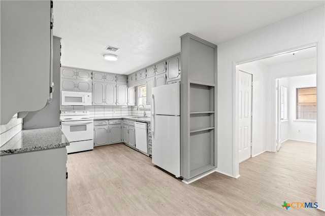 kitchen featuring light wood-type flooring, a wealth of natural light, sink, and white appliances