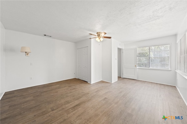 spare room featuring hardwood / wood-style flooring, ceiling fan, and a textured ceiling