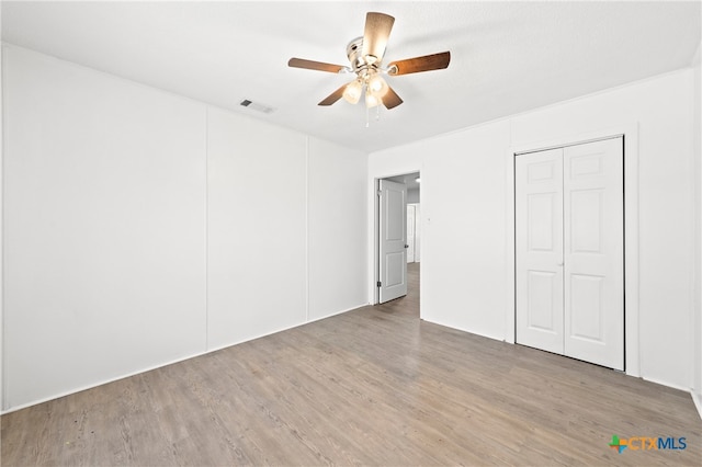 unfurnished bedroom with a closet, hardwood / wood-style floors, and ceiling fan