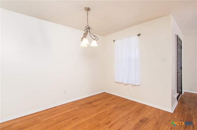 empty room featuring a chandelier and hardwood / wood-style floors