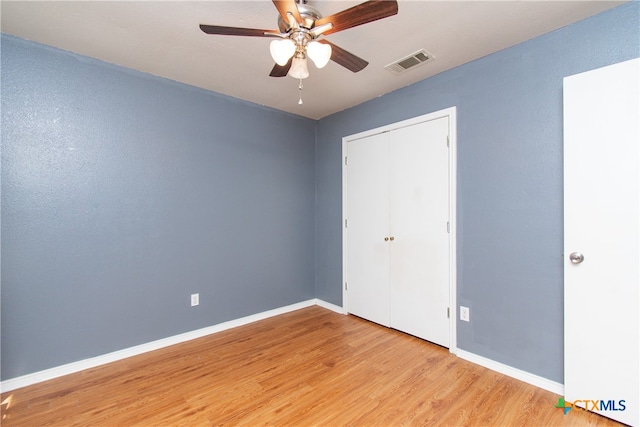 unfurnished bedroom featuring light hardwood / wood-style flooring, ceiling fan, and a closet