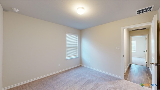 spare room featuring baseboards, visible vents, and light carpet