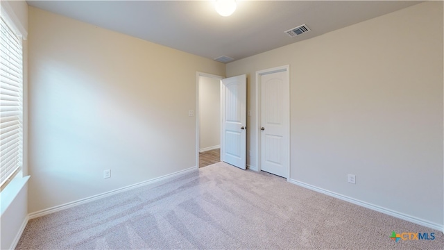 unfurnished bedroom with baseboards, visible vents, and carpet
