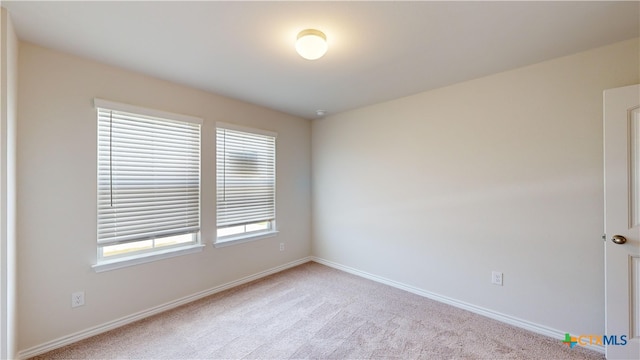 spare room featuring carpet and baseboards