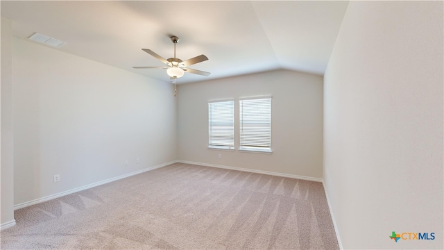 spare room featuring a ceiling fan, baseboards, vaulted ceiling, and light colored carpet