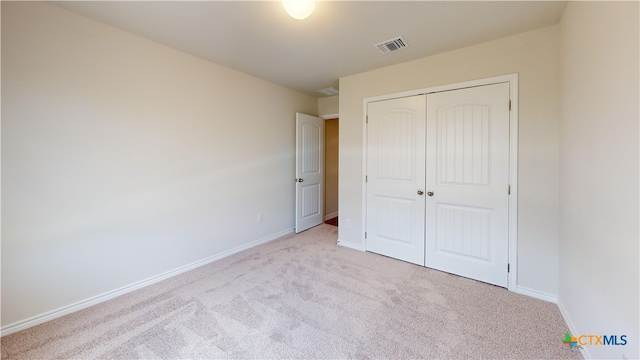 unfurnished bedroom featuring baseboards, visible vents, a closet, and carpet flooring