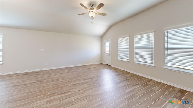 unfurnished room with ceiling fan, lofted ceiling, light wood-style floors, and baseboards