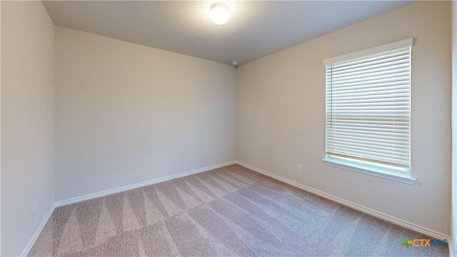 carpeted spare room featuring baseboards
