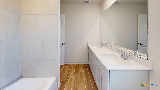 full bath featuring visible vents, wood tiled floor, a sink, and double vanity