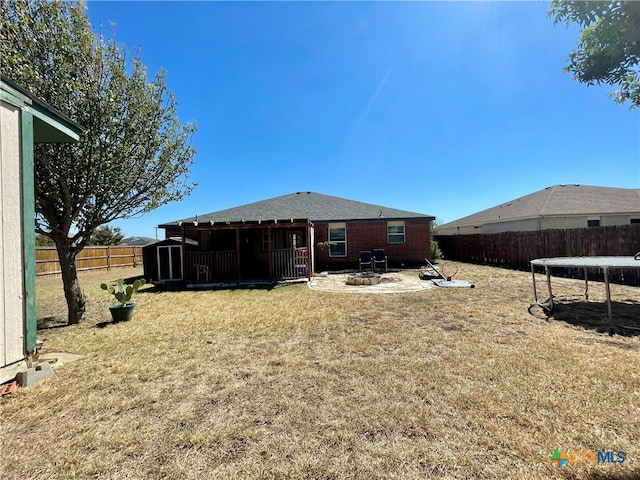 rear view of property featuring a lawn and an outdoor fire pit