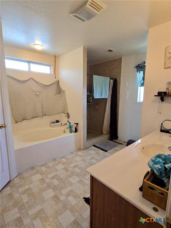 bathroom with vanity, a textured ceiling, and independent shower and bath