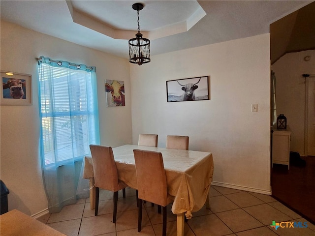 dining space with a notable chandelier, tile patterned floors, and a raised ceiling