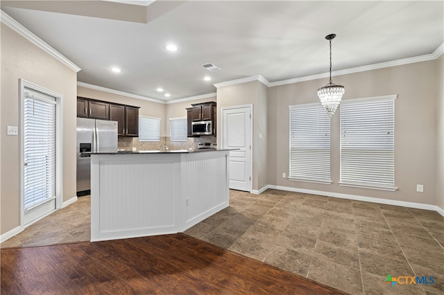 kitchen featuring stainless steel appliances, hanging light fixtures, a kitchen island, dark brown cabinetry, and tasteful backsplash