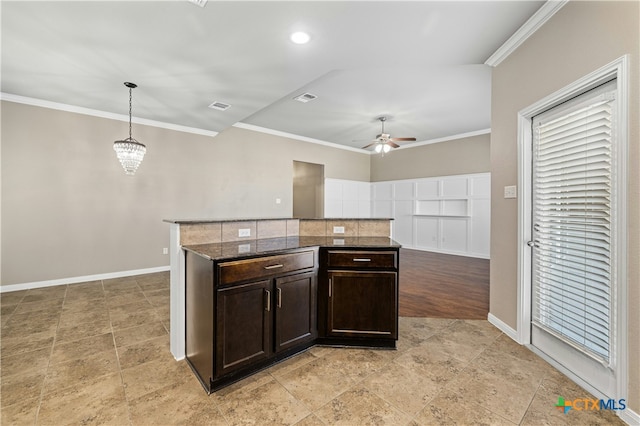 kitchen featuring decorative light fixtures, ceiling fan with notable chandelier, dark stone counters, ornamental molding, and dark brown cabinetry