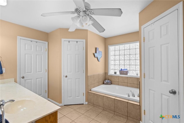 bathroom featuring vanity, a relaxing tiled tub, tile patterned floors, and ceiling fan