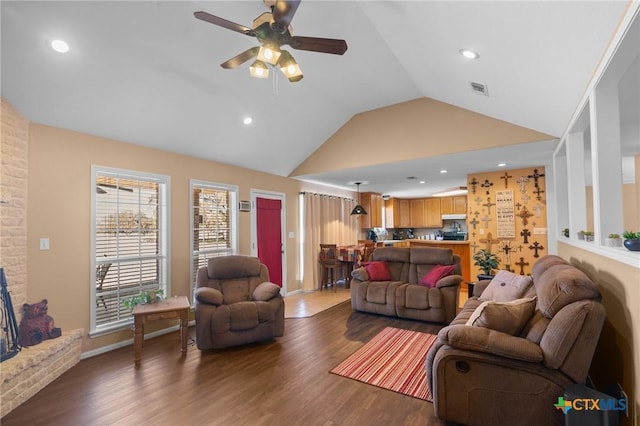 living room featuring ceiling fan, dark hardwood / wood-style flooring, vaulted ceiling, and a fireplace