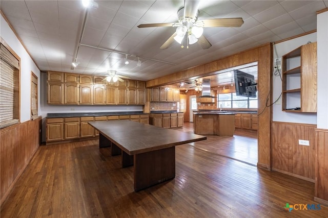 kitchen featuring dark countertops, wainscoting, island exhaust hood, and wood walls