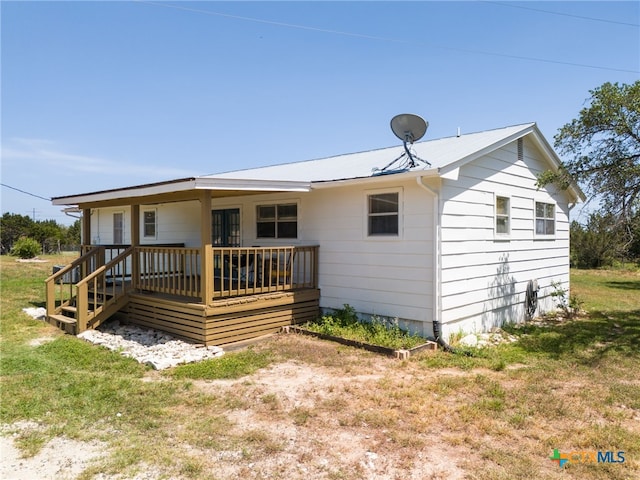 rear view of house with a yard and a wooden deck